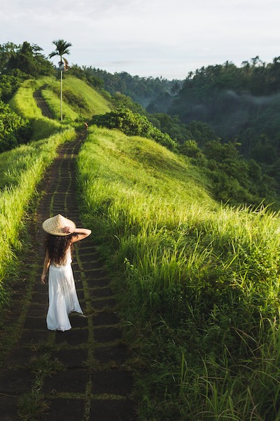 Kvinna som går på Campuhan Ridge, konstnärernas väg, i Bali, Ubud. Vacker lugn solig morgon.