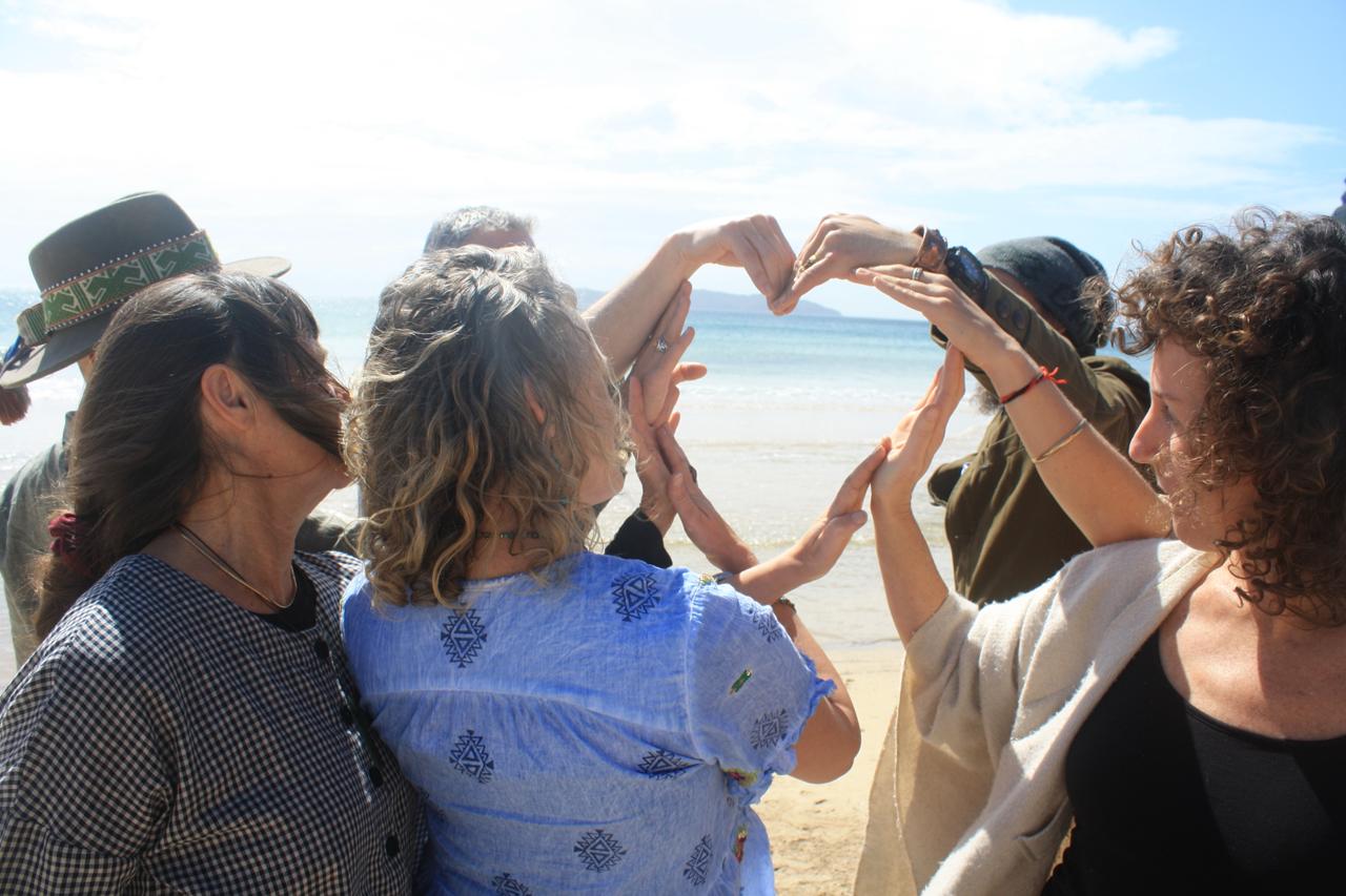 Empathy Angels team members forming a heart shape with their hands on the beach