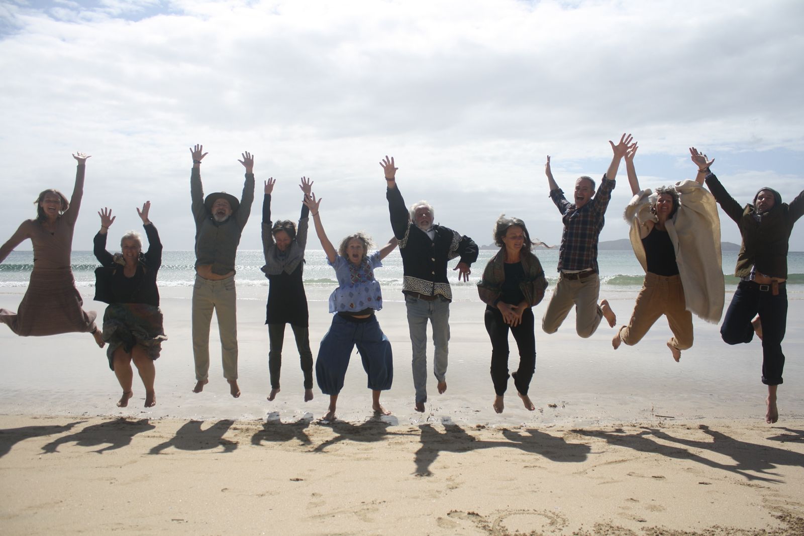 The Empathy Angels team jumping joyfully on a beach in Kaitaia, New Zealand