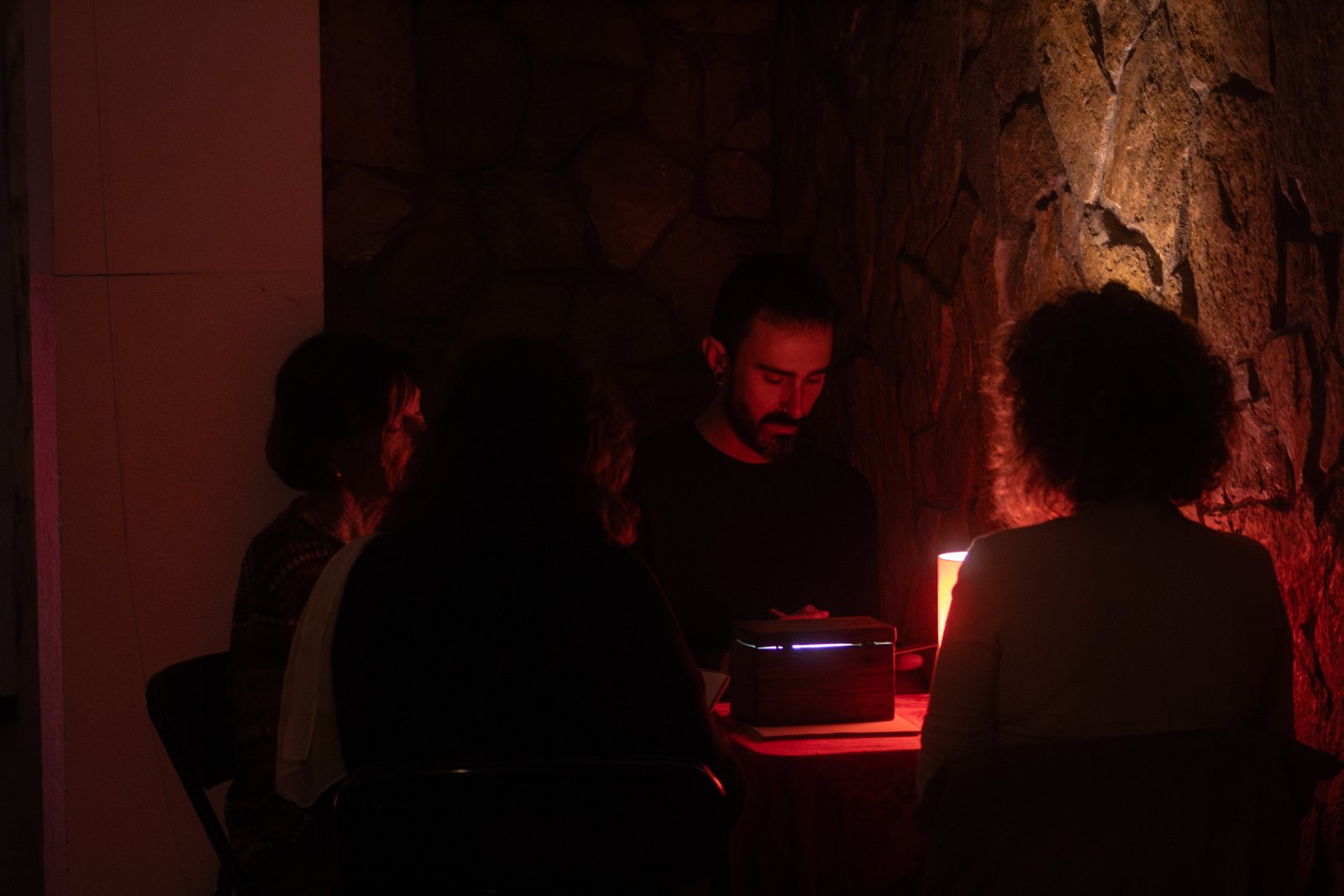 A small group gathered around a table in low red light