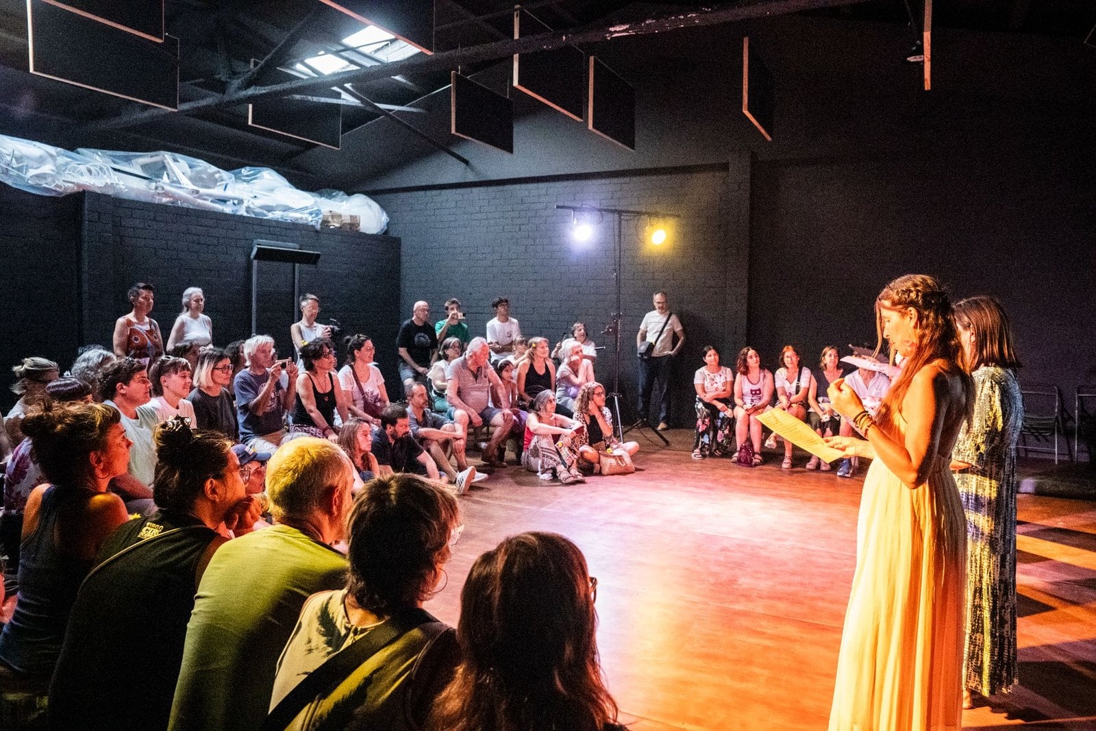 A public presentation of the h(ovo) project, with a large audience gathered around two performers